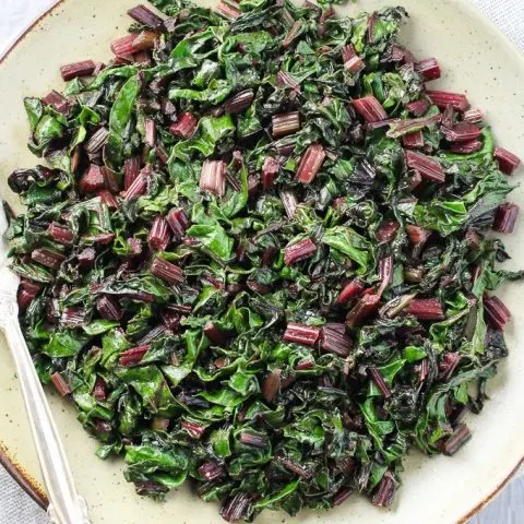 Top view of the sauteed beet greens on a plate with a fork.