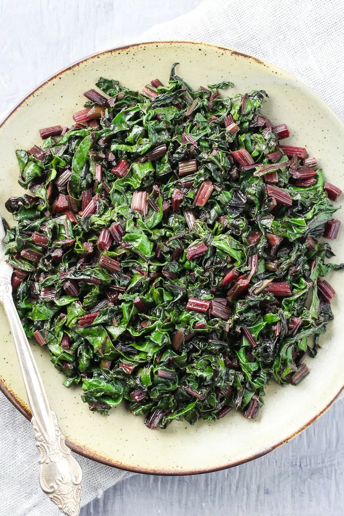 Top view of the sauteed beet greens on a plate with a fork.