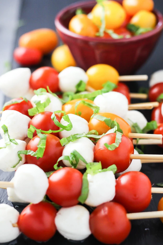 A side-view of the small mozzarella cheese balls and cherry tomatoes arranged on toothpicks.