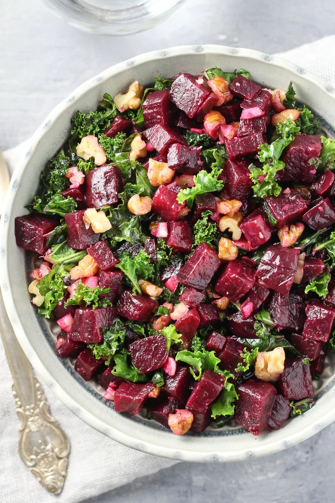 Top view of the detox kale and beet salad in a bowl standing on a grey board.