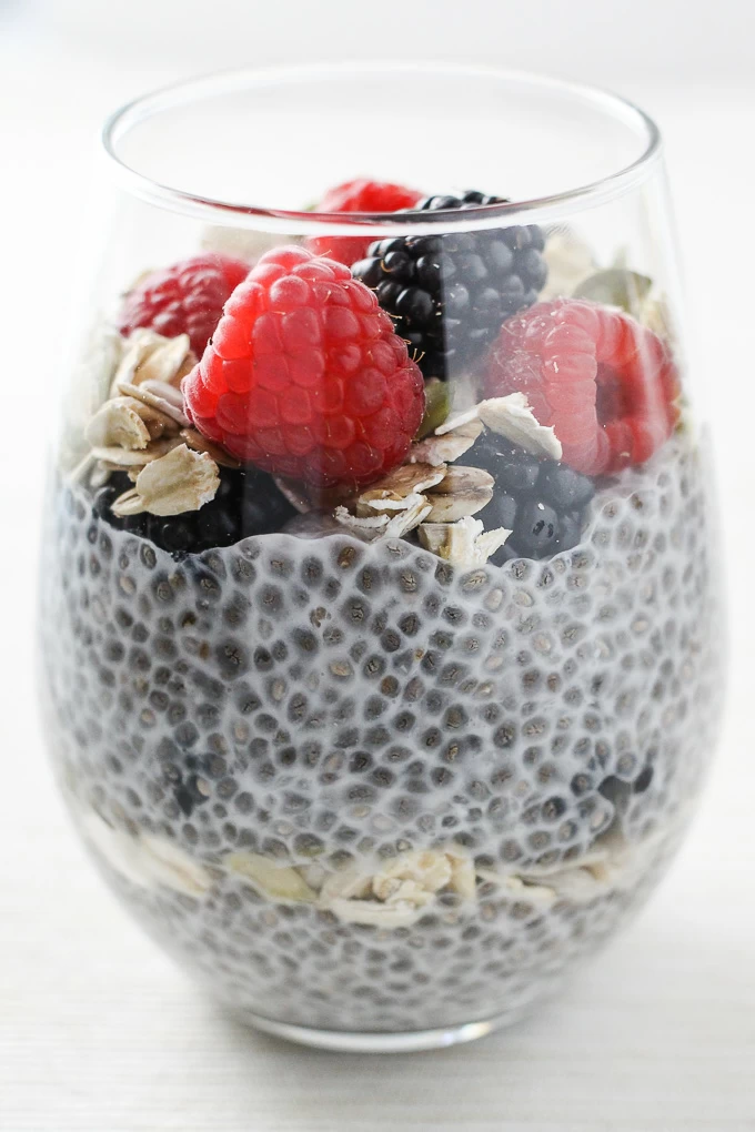 A close-up side view of the very berry chia pudding breakfast parfait in a glass.