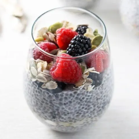 A side view of the chia pudding breakfast parfait in a glass, topped with berries.