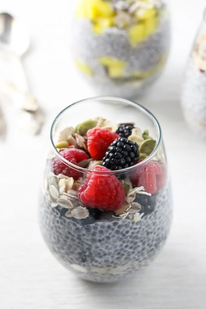 A side view of the chia pudding breakfast parfait in a glass, topped with berries..