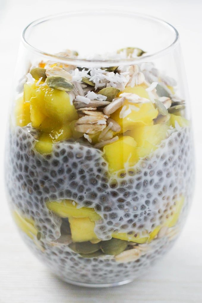 A close-up side view of the mango coconut chia pudding breakfast parfait in a glass.