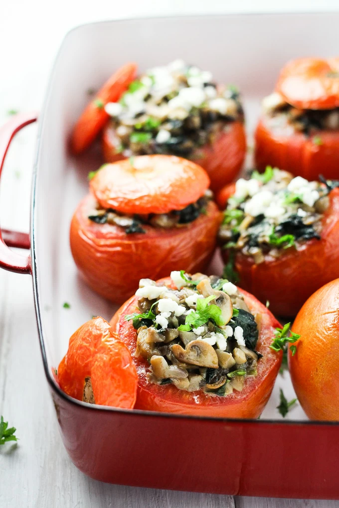 Vegetarian stuffed tomatoes in a red baking dish.