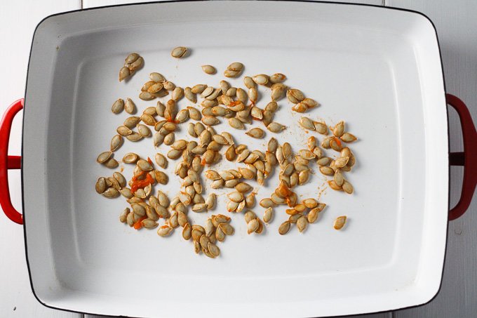 A top view of butternut squash seeds in a white baking dish.