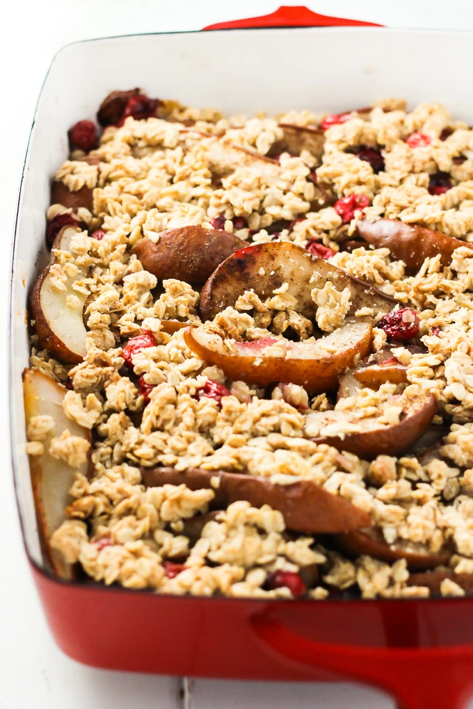 A close-up side view of the pear cranberry crisp in a red baking dish.