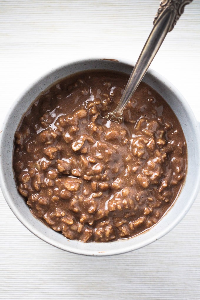 Top view of the hot chocolate oatmeal in a grey bowl with a spoon in the oatmeal.