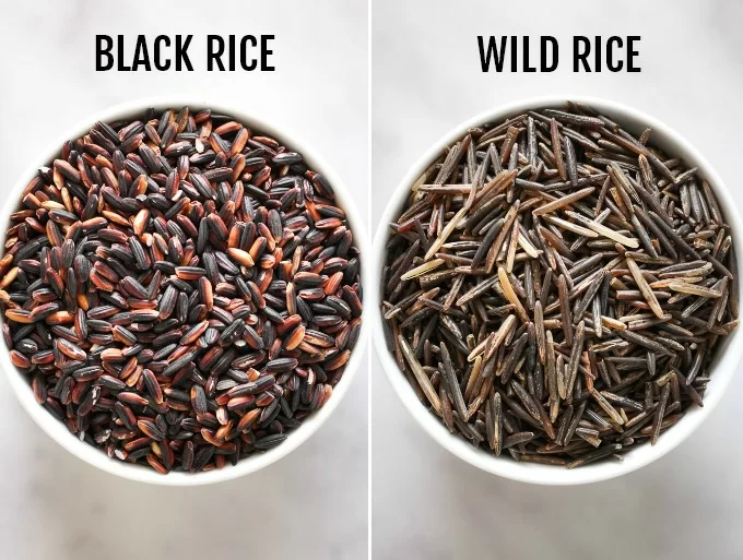Black rice in a small bowl on the left vs. wild rice in a small bowl on the right.