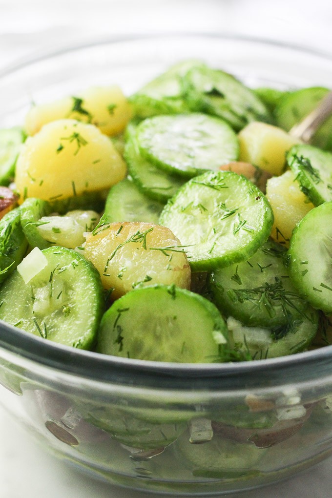 Potato cucumber salad in a glass bowl. Side view.