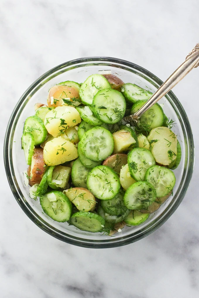 Potato cucumber salad in a glass bowl. Top view.
