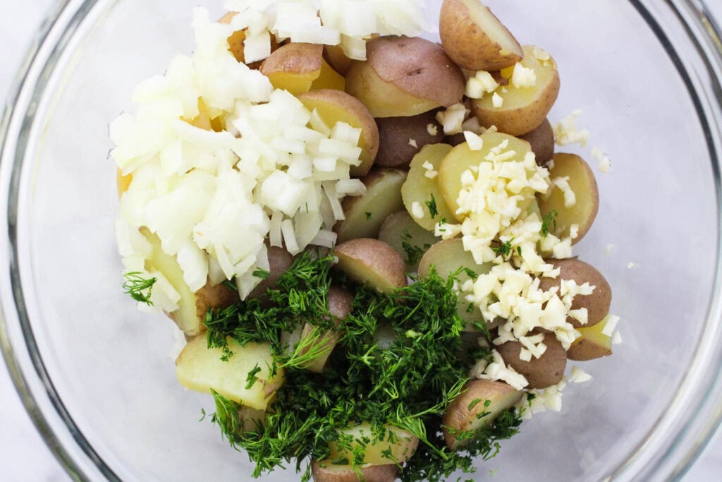 Potatoes, onions, garlic and dill in a bowl.
