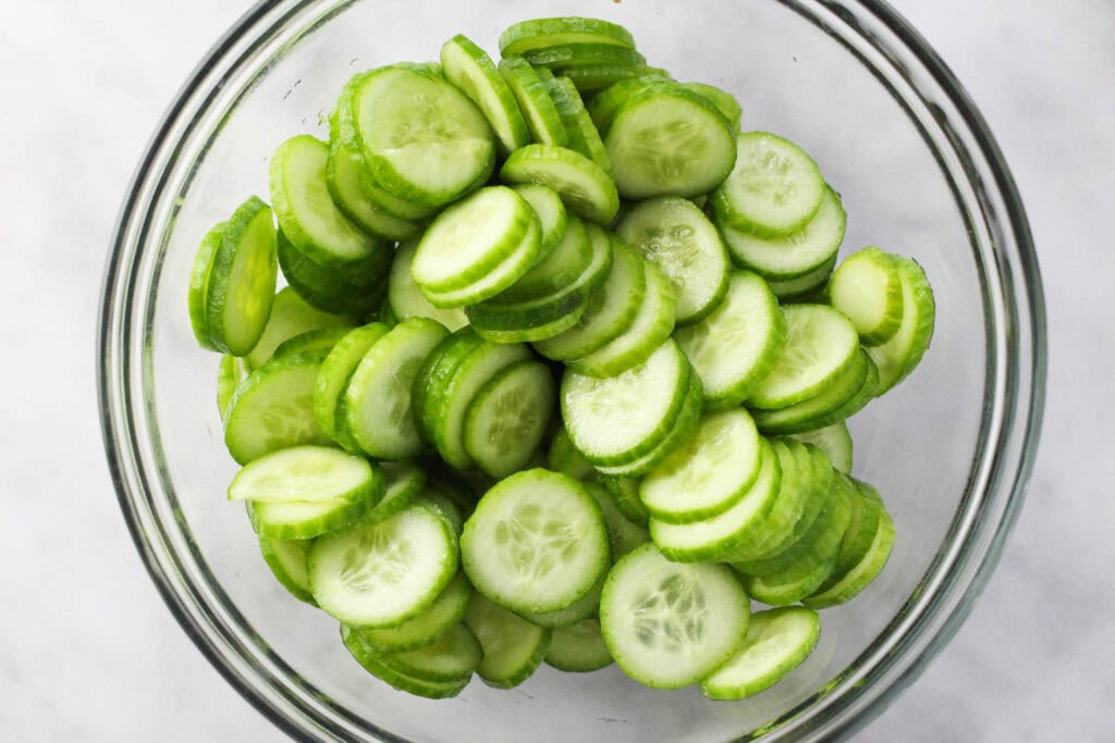 Thinly sliced cucumbers being prepared for potato cucumber salad.