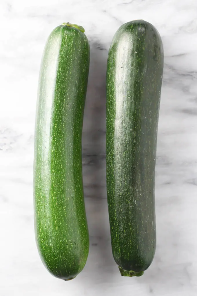 Two fresh zucchini on marble background.