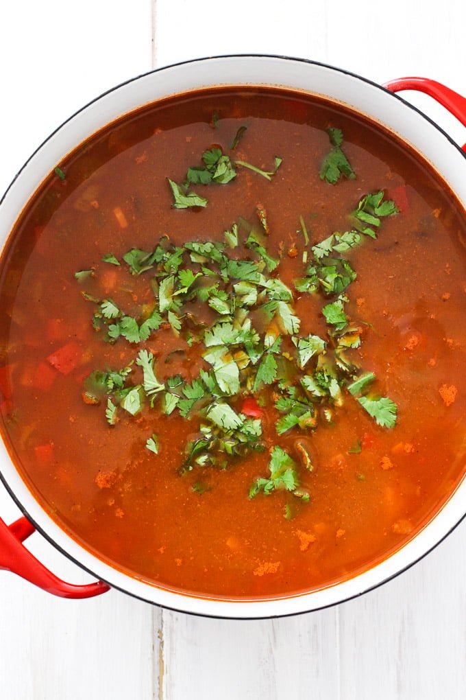 Black bean soup in a pot garnished with fresh cilantro. Top view.