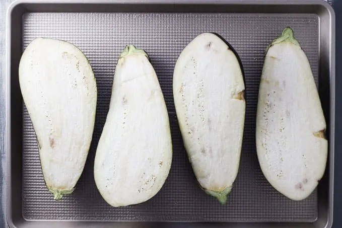 Eggplants on a baking sheet. Cut in half lengthwise. Cut side up.