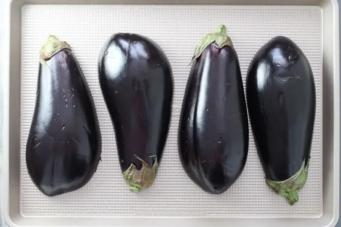 Eggplants on a baking sheet. Cut in half lengthwise. Cut side down.