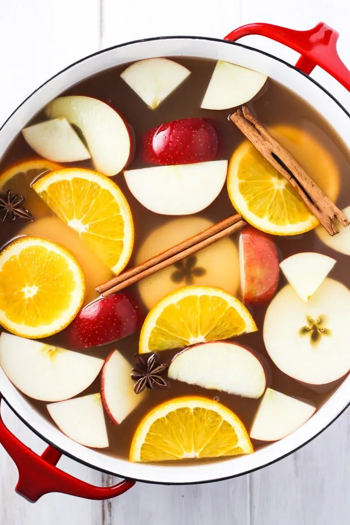 Hot apple cider in a pot. Garnished with orange and apple slices, star anise, and cinnamon sticks. Top view.