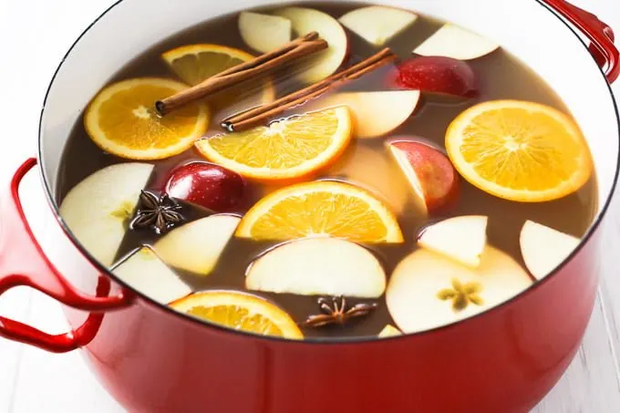 Hot apple cider in a pot. Garnished with orange and apple slices, cinnamon sticks, and star anise.