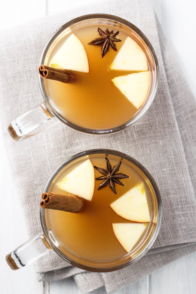 Hot apple cider in glasses. Garnished with star anise, apple slices, and cinnamon sticks. Top view.