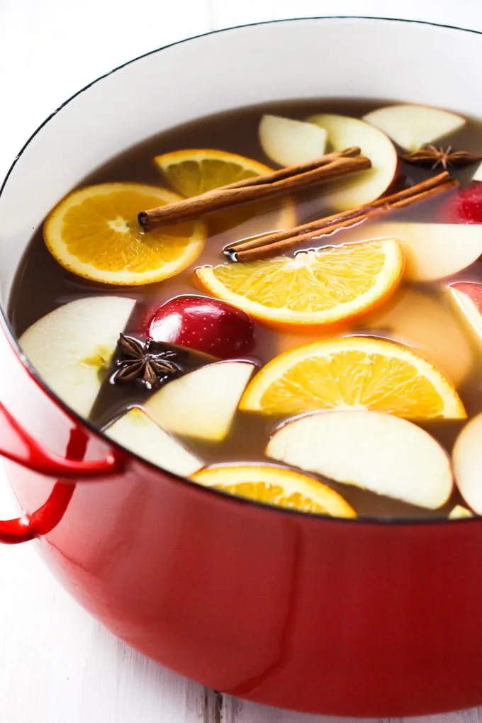Hot apple cider in a pot. Garnished with orange and apple slices and cinnamon sticks.