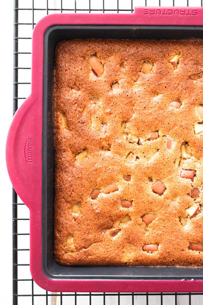 Healthy apple cake in a baking pan on a cooking rack.