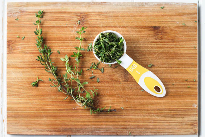 Thyme leaves and steams on a cutting board.