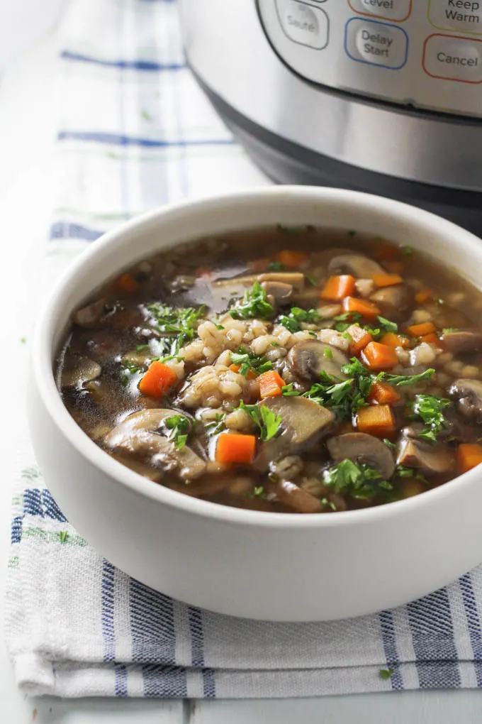 Mushroom barley soup in a bowl with the Instant Pot in the background.