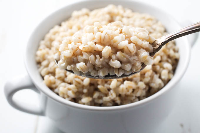 Cooked pot barley on a silver spoon.