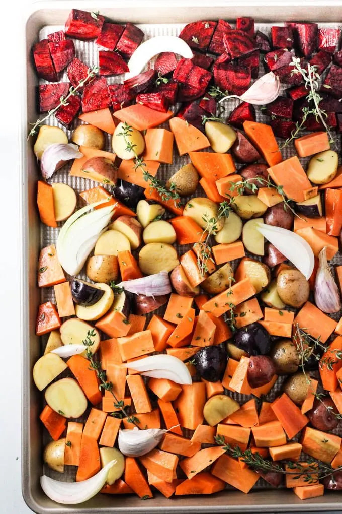 Raw chopped root vegetables on a baking sheet.
