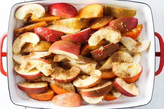 Fruit slices in a baking dish sprinkled with lemon zest and cinnamon.