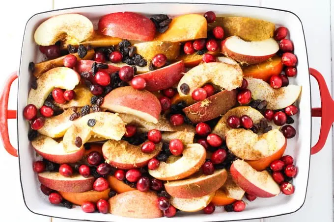 Fruit slices, cranberries, and raisins in a baking dish.