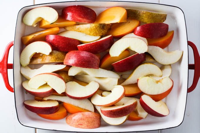 Apple, pear, and persimmon slices in a baking dish.