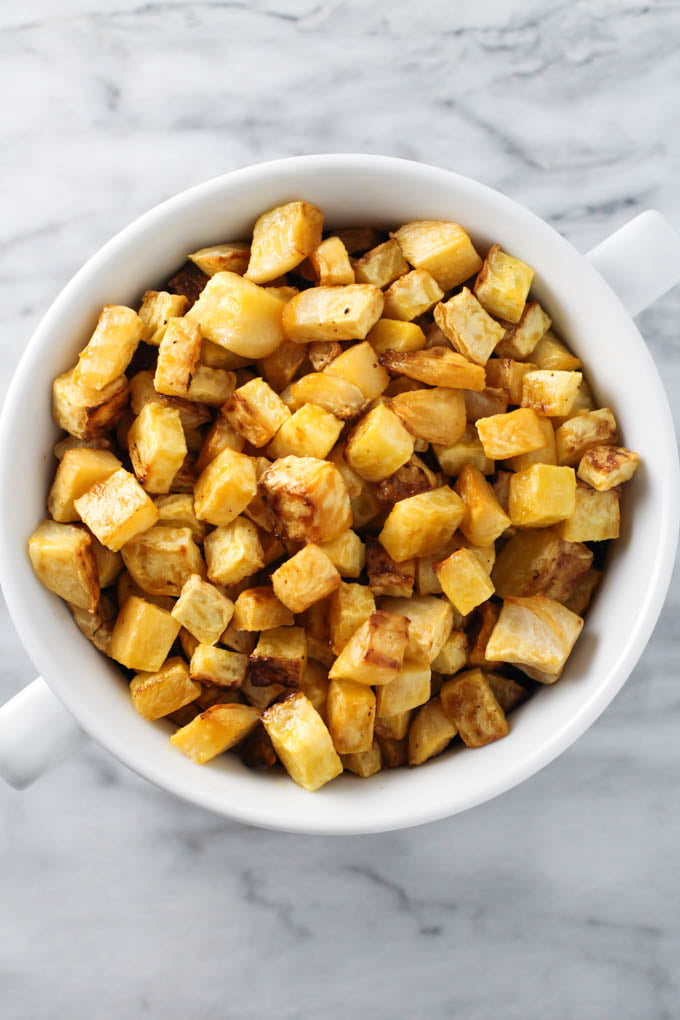 Roasted Rutabaga in a white dish on marble background. Top view.