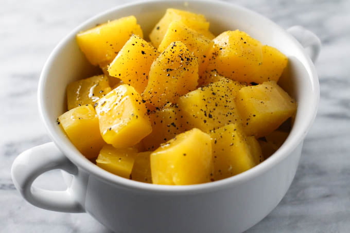 Boiled rutabaga in a white dish. Seasoned with ground black pepper.