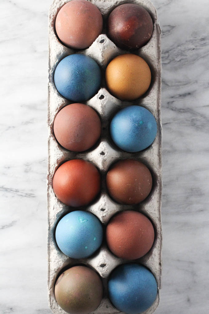 Easter eggs in an egg carton on a marble background.