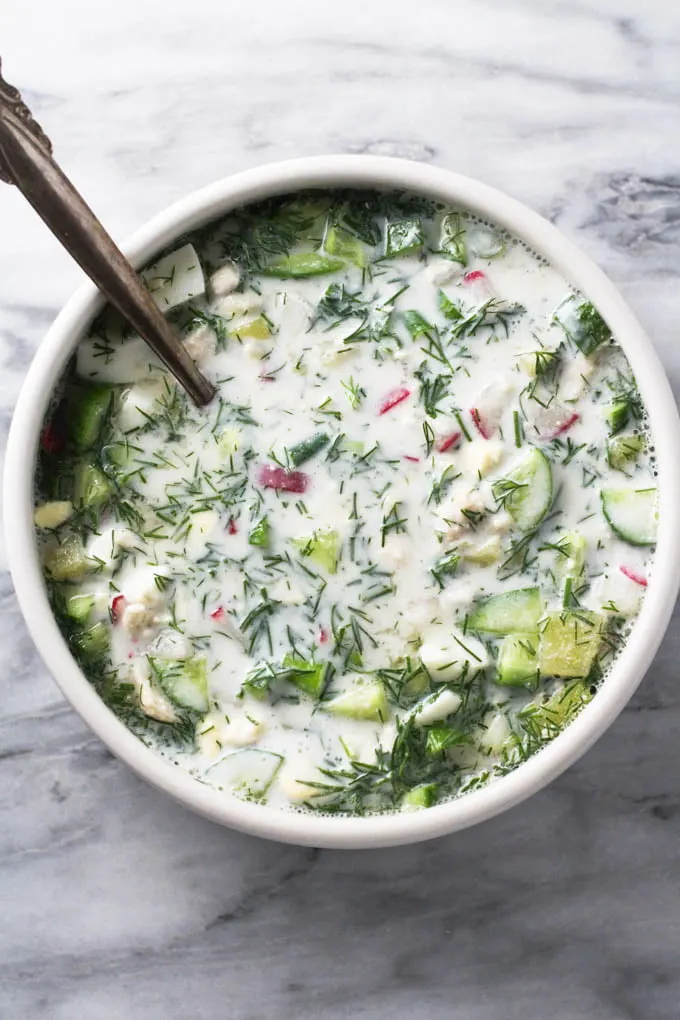 Top view of okroshka soup in a bowl on marble background.