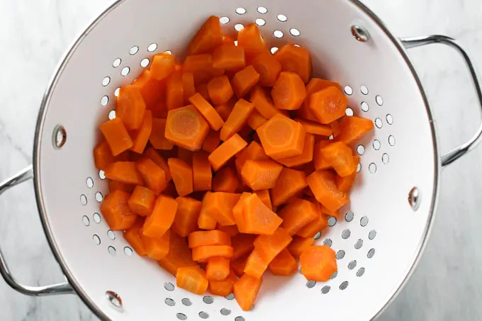 Parboiled carrots inside a colander.