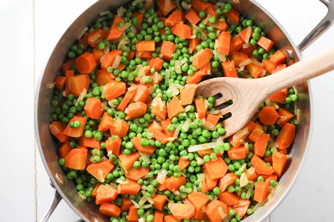 Top view of peas and carrots in a pan.