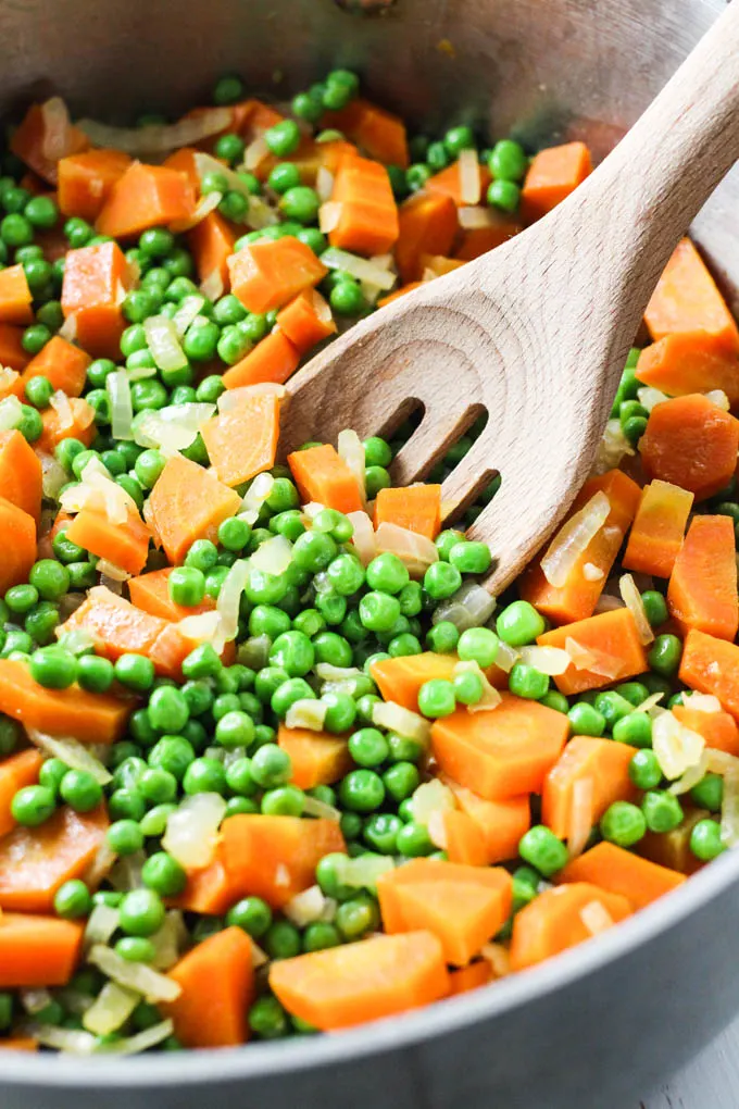 Close up of peas and carrots in a pan.