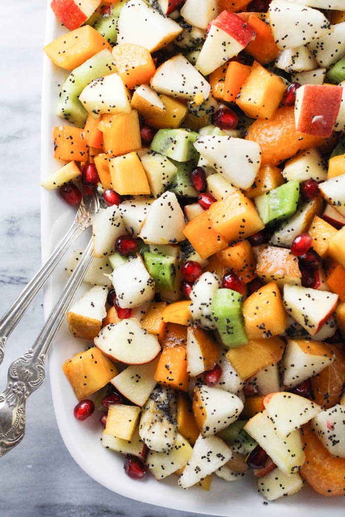 Fall and winter fruit salad on a platter standing on a marble background.