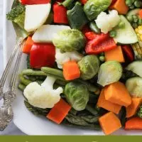 Instant Pot steamed vegetables on a white platter with silver serving spoons to the left. Under the image, there are words: Instant Pot Steamed Vegetables.