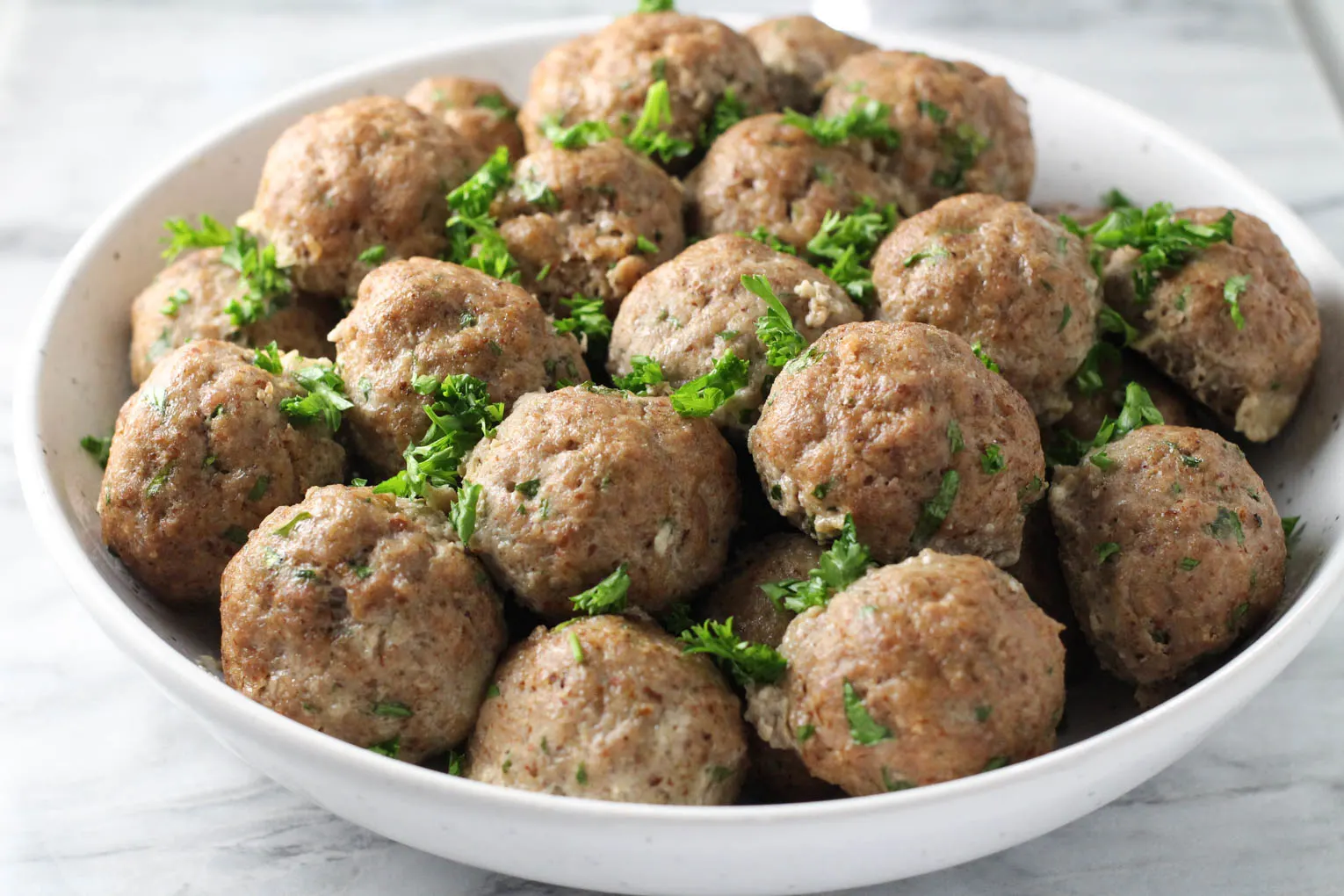 Side view of meatballs in a white bowl.