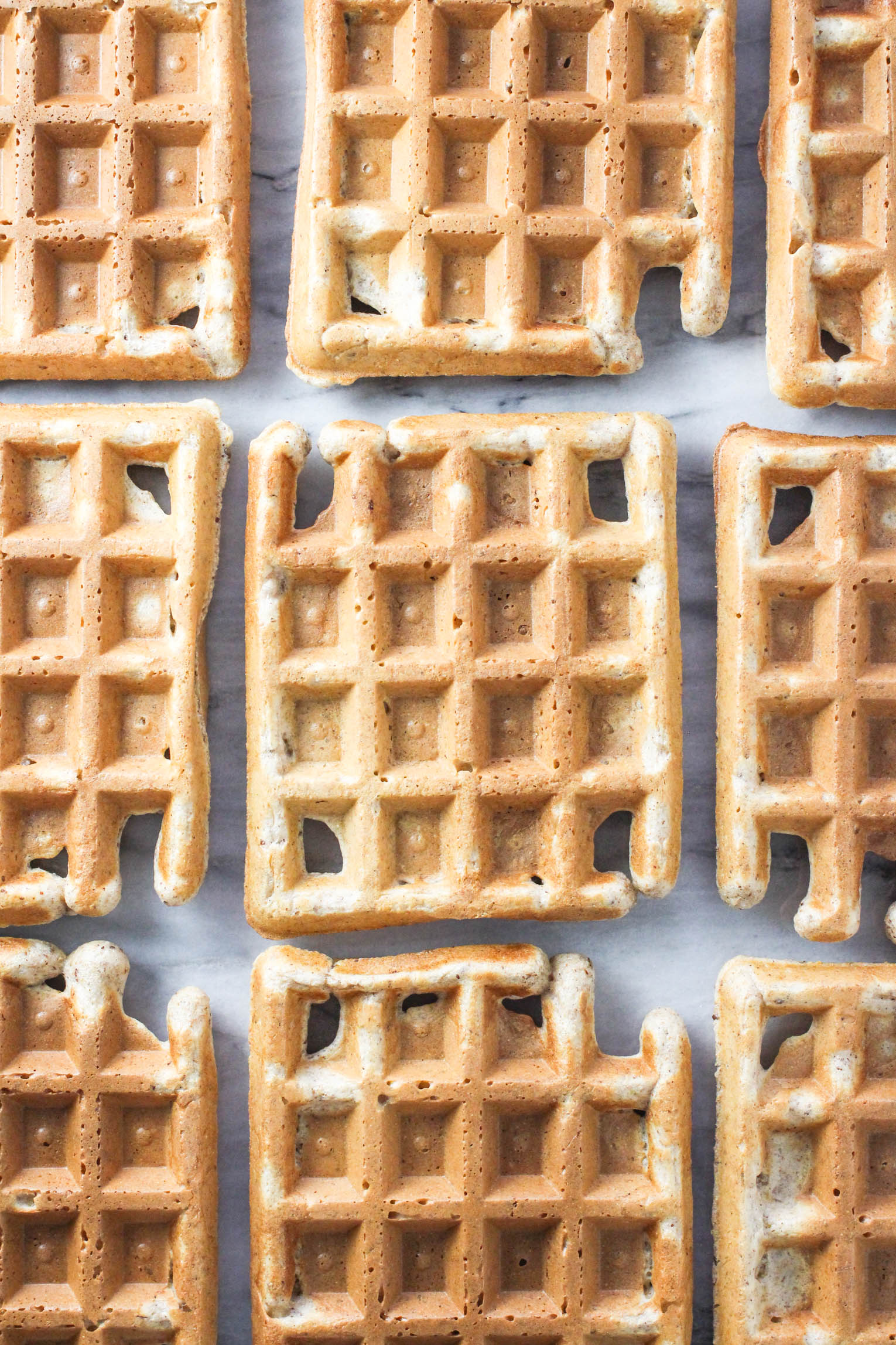 An overhead shot of whole wheat waffles laying on a marble background.