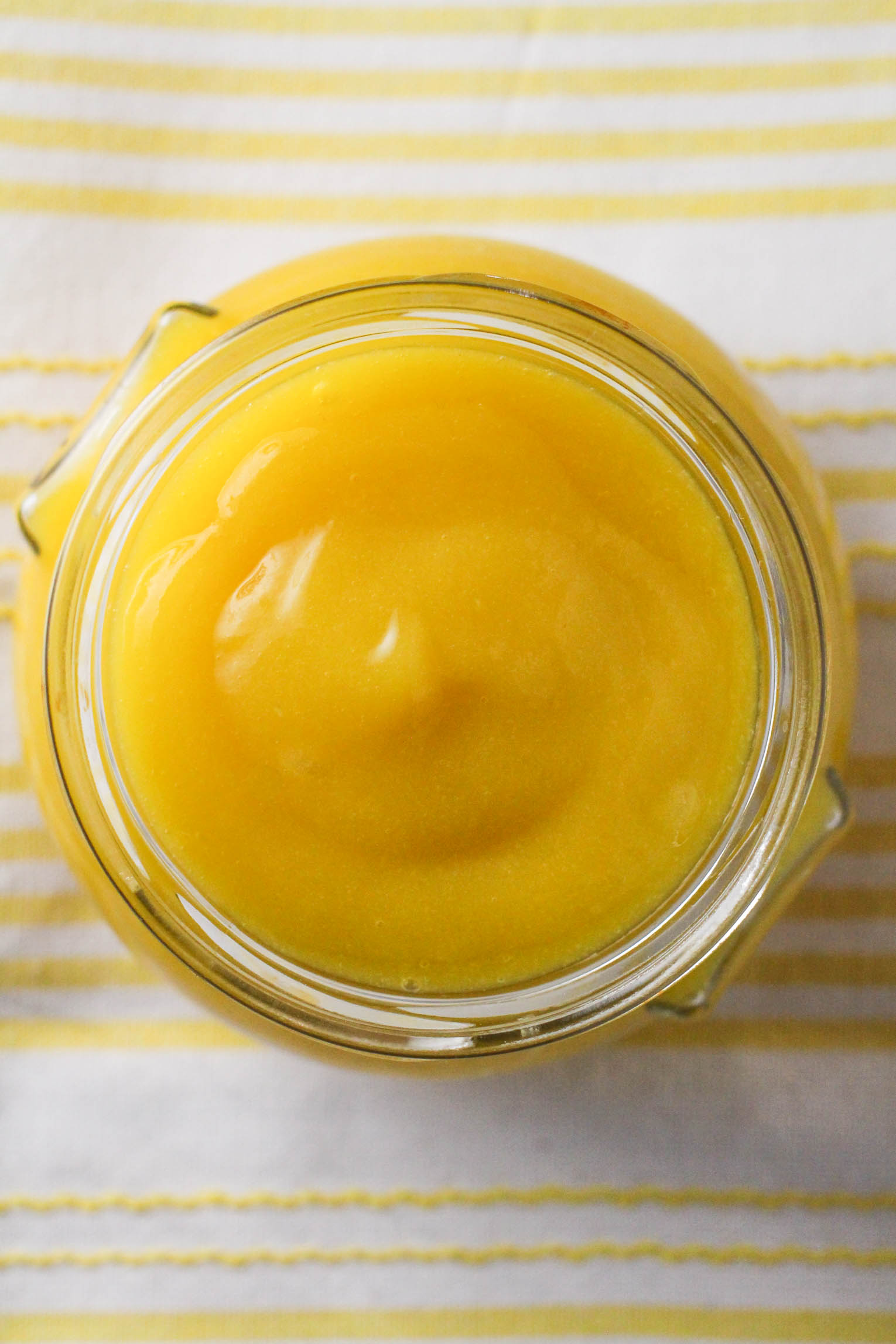 Top view of the mango puree in a glass jar standing on a kitchen towel.