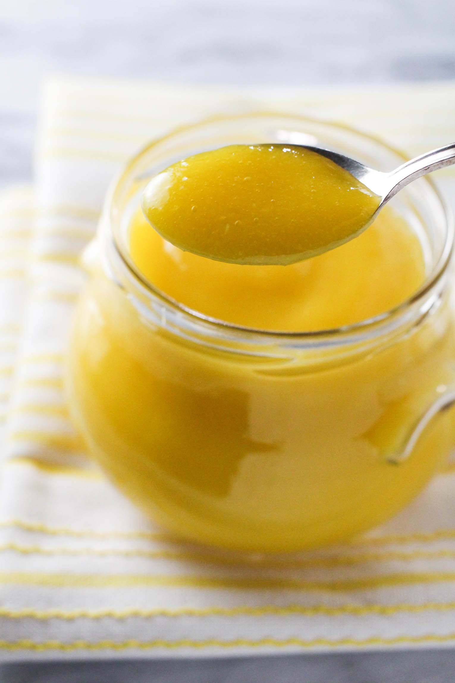 Close up shot of the mango puree being scooped out of a glass jar with a spoon.