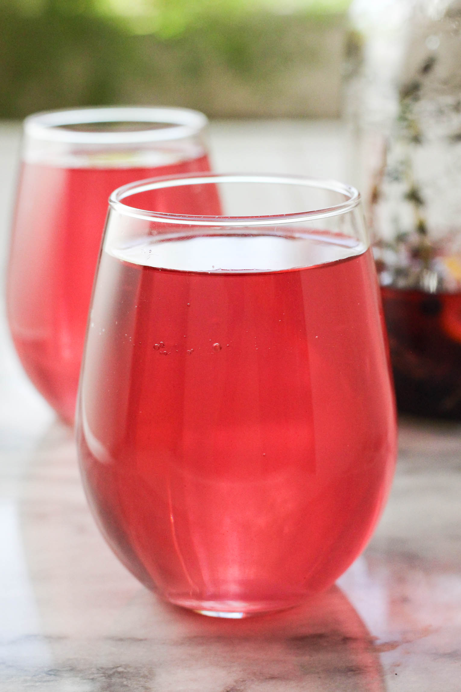 A glass with blueberry water. Another glass in the background.