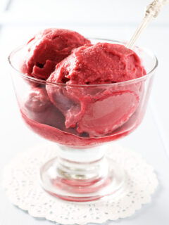Raspberry ice cream in a glass bowl.