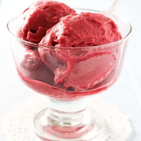 Raspberry ice cream in a glass bowl.