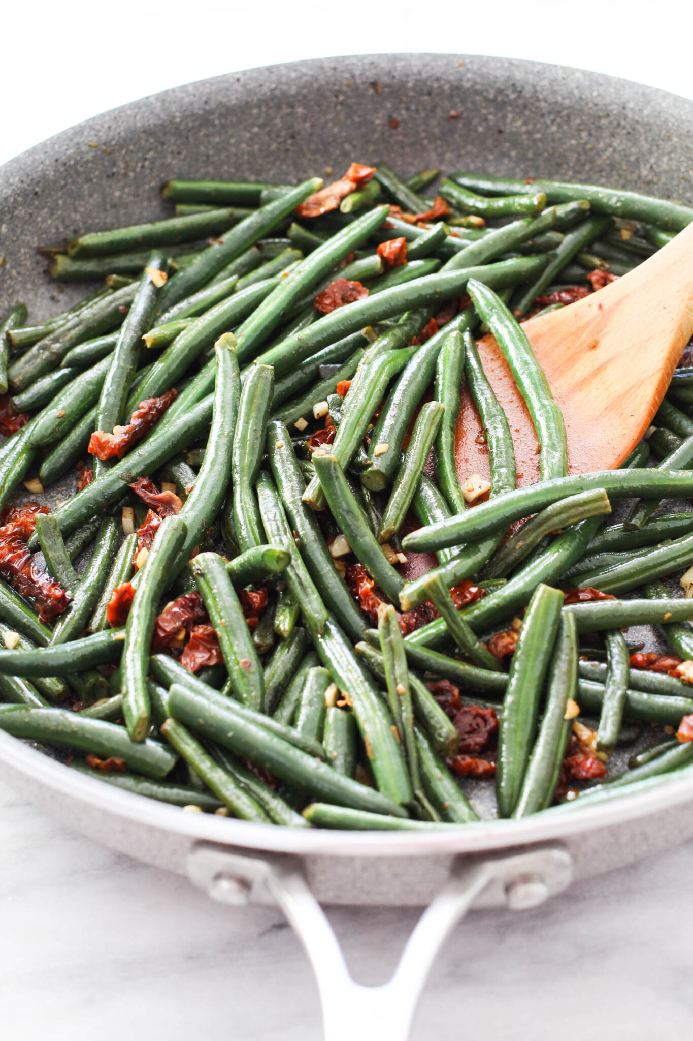Green beans with sun-dried tomatoes and garlic in a skillet.